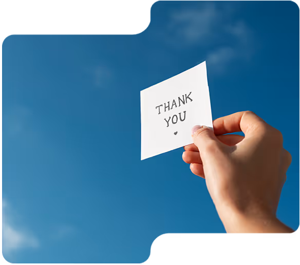Hand hält Zettel mit Aufschrift 'Thank You' vor blauem Himmel.