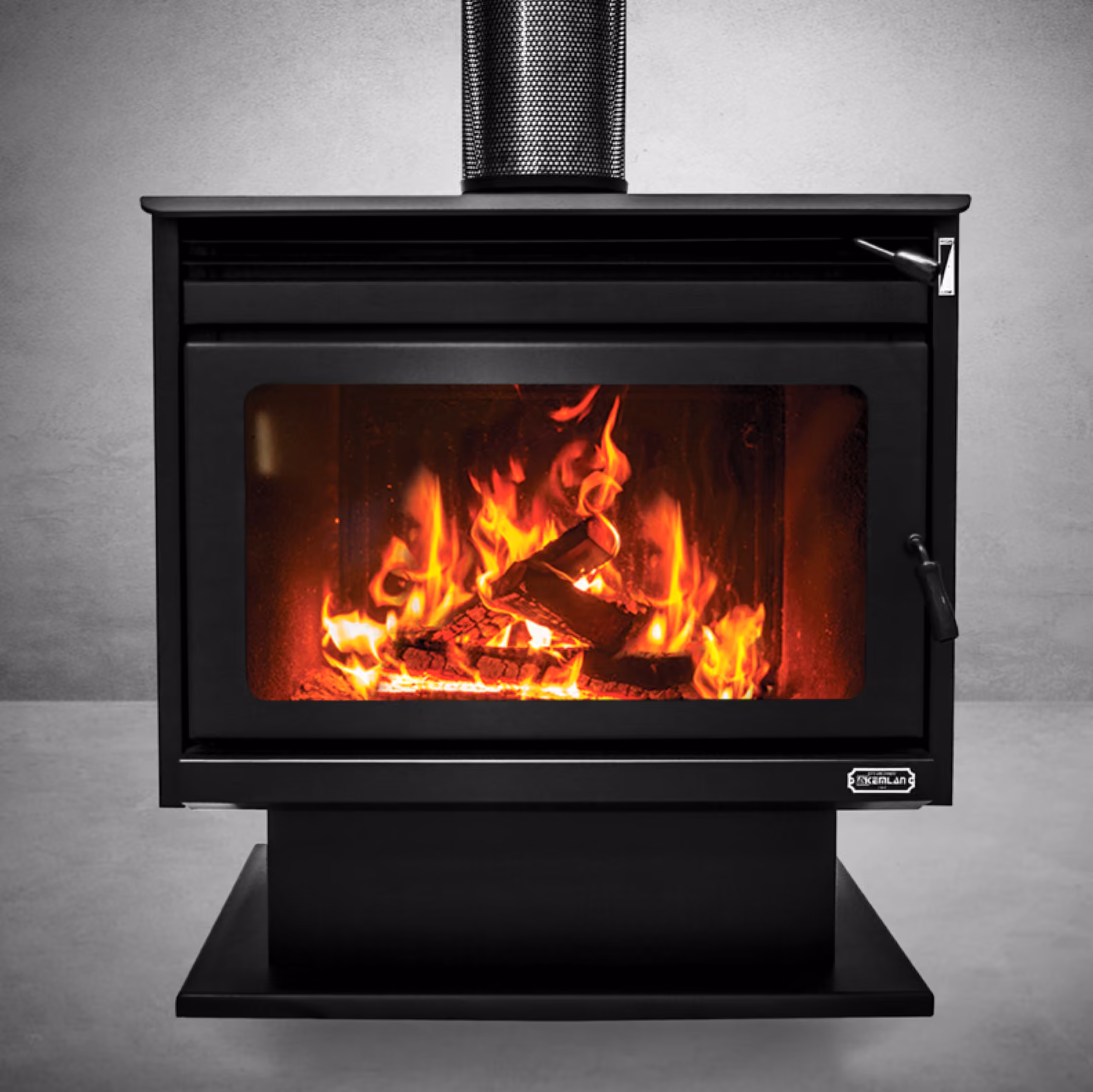 Modern black wood-burning stove with visible flames inside in a showroom with signs and office desks.