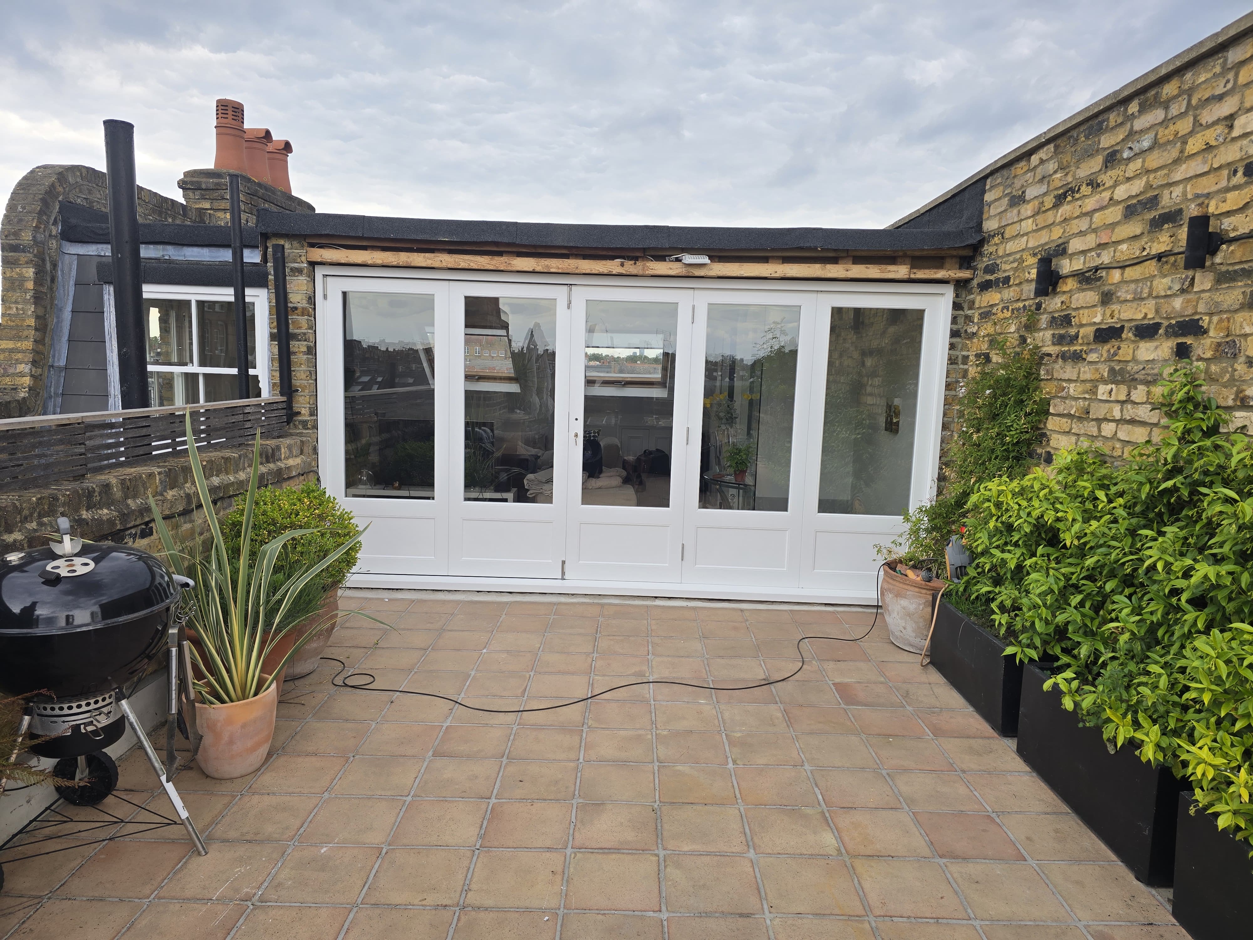 White timber bi-fold doors installed on London rooftop terrace by AMB Joinery