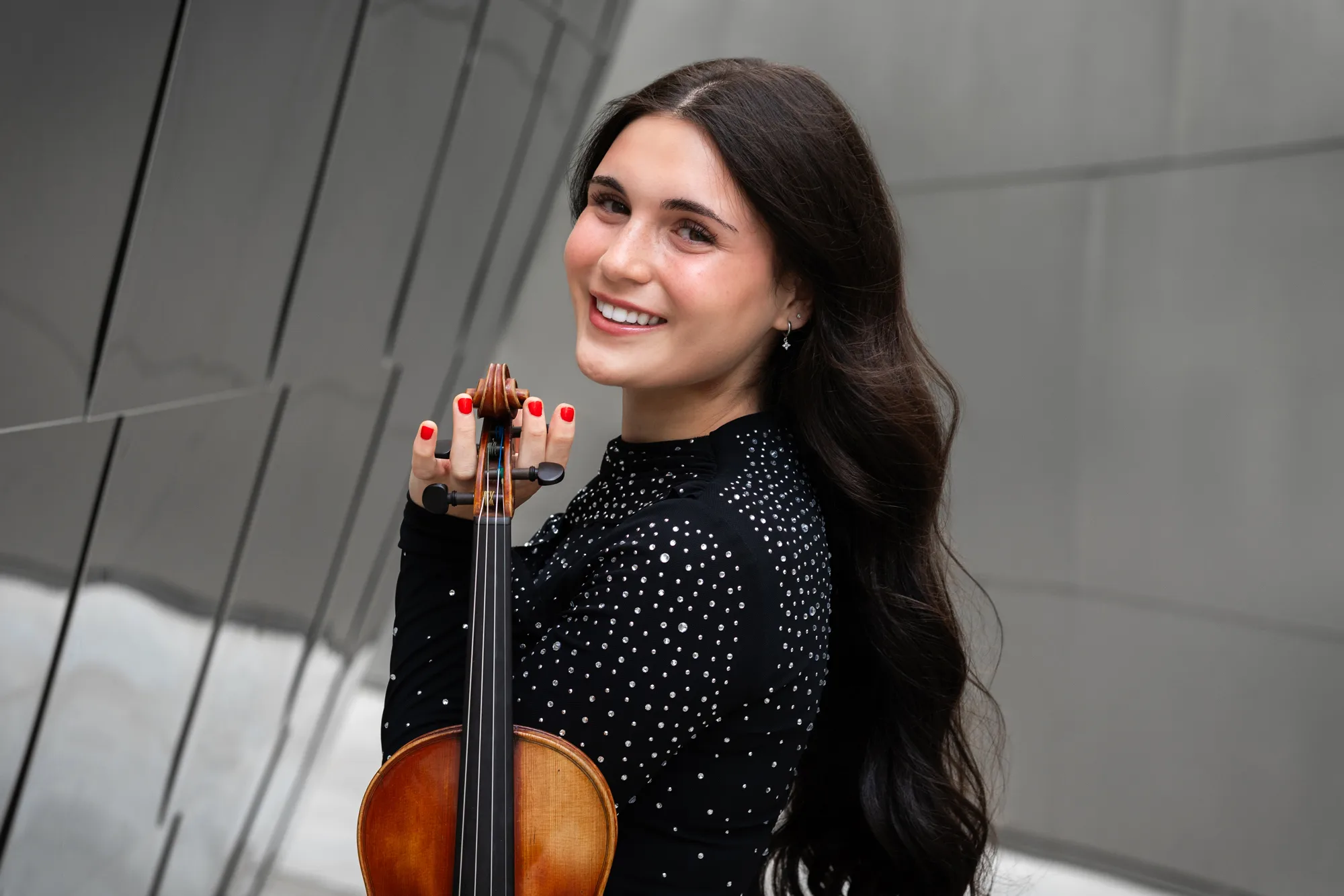 Portrait of Nesya smiling, holding her violin