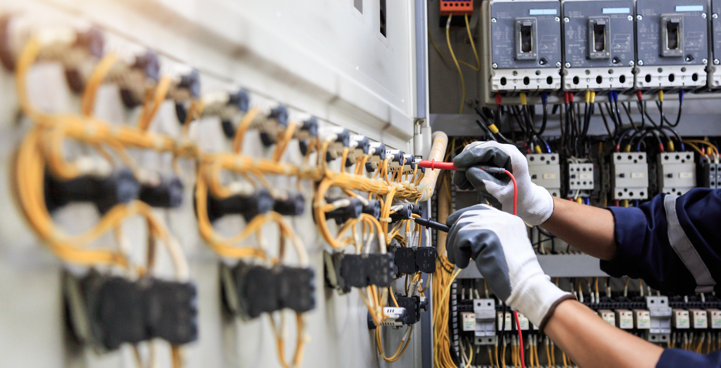 Electrician testing terminal blocks in an electrical control panel with multimeter probes