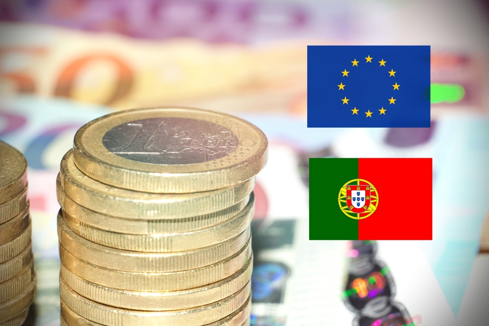 A stack of €1 euro coins on top of euro notes with an EU and Portugal flag