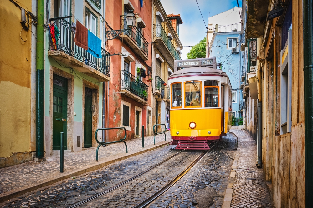 ellow Tram 28 climbing a narrow, steep cobblestone street in Lisbon,