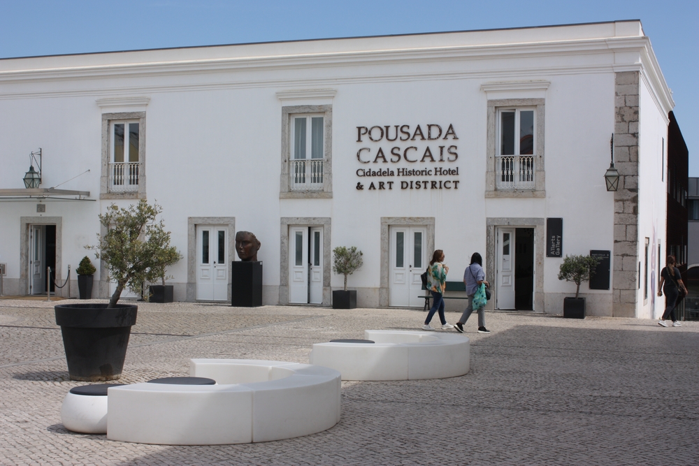 Exterior of Pousada Cascais hotel and art district, in Cascais, with white walls and stone courtyard