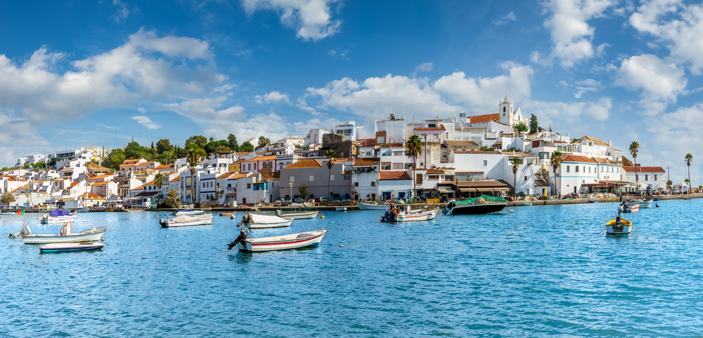 Colorful white buildings and small fishing boats in the harbor of a coastal Portuguese town