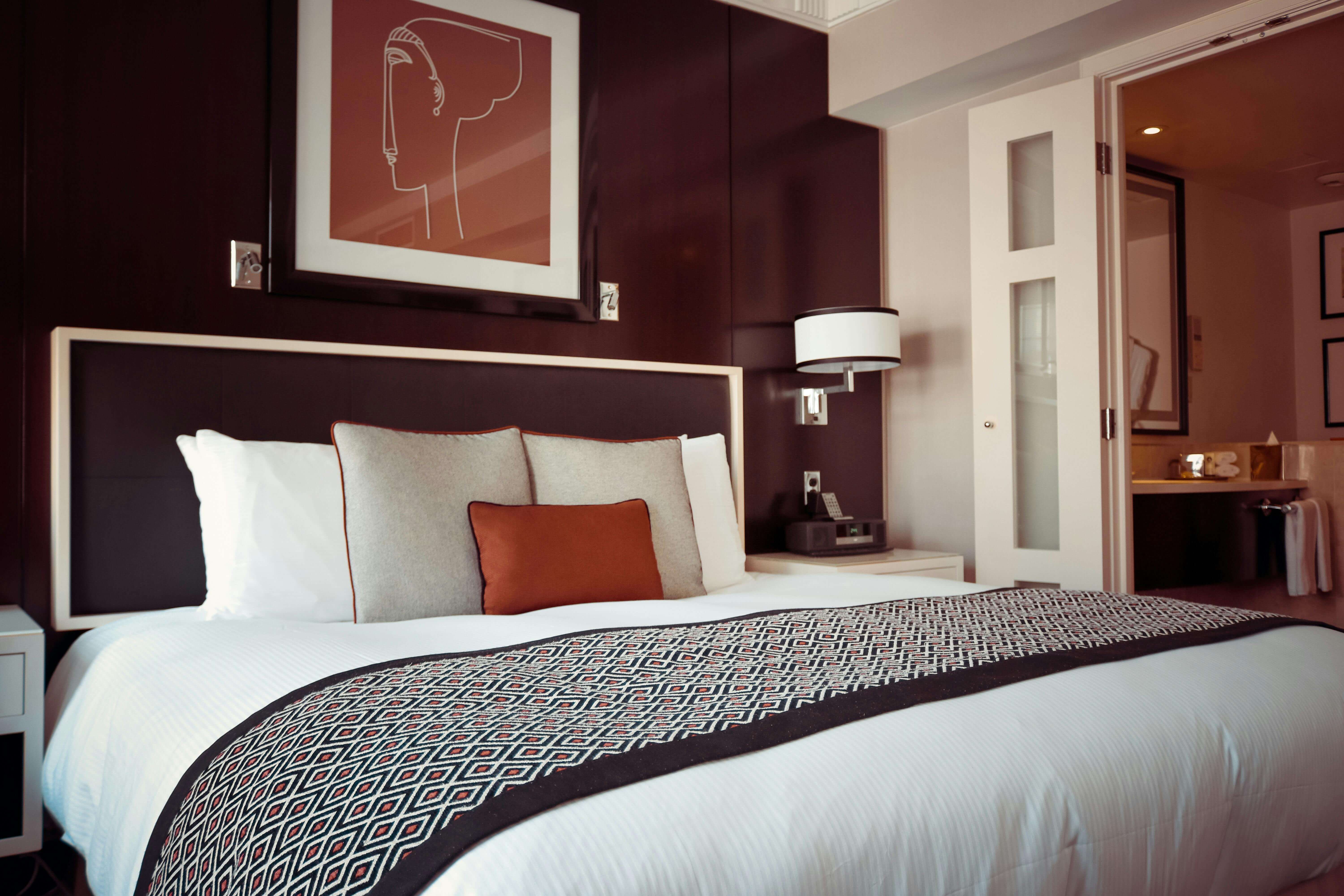Luxury hotel room with a modern bed, dark wood headboard, and minimalist art on the wall