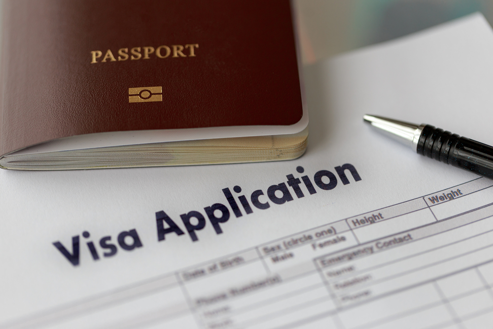 Visa application form next to a passport and a pen on a desk