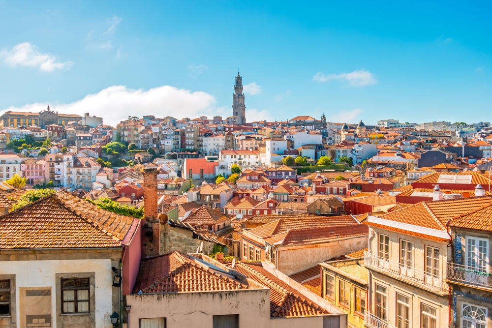 Cityscape of Porto with colorful buildings and the Clerigos Tower under a blue sky