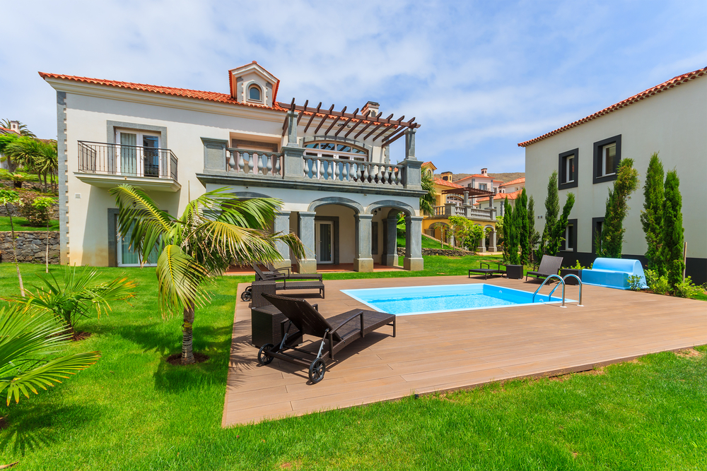 Luxury villa with a private swimming pool, sun loungers, and a lush green lawn