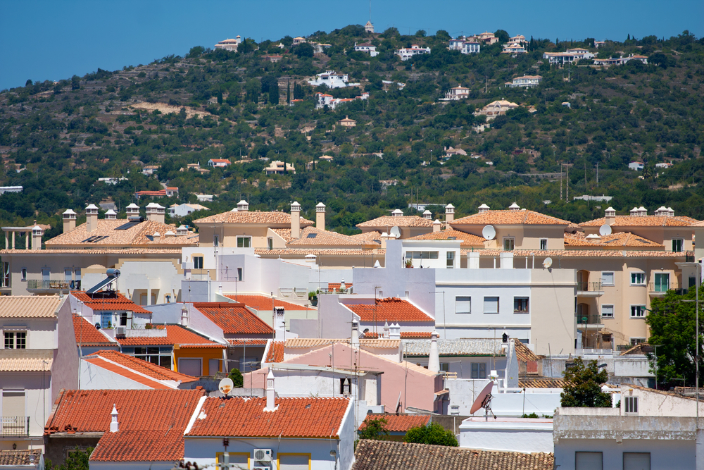 Red-tiled roofs of white houses in Loulé with a green hillside in the distance