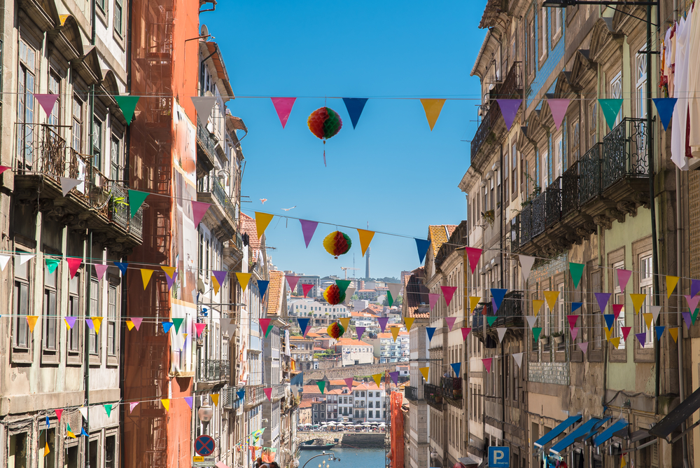 Narrow street in Porto decorated with colorful festival flags and paper lanterns