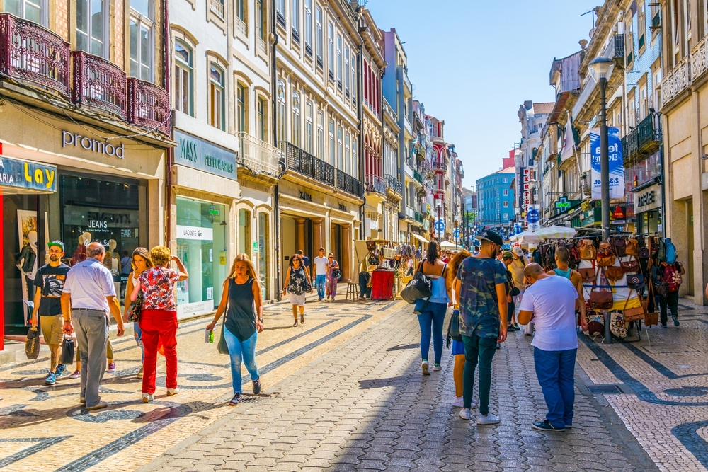 Crowded pedestrian shopping street in Porto, with historic buildings and shops