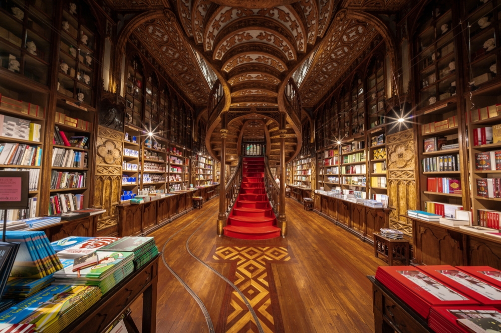 Interior of Livraria Lello bookstore in Porto featuring ornate wood and a red staircase
