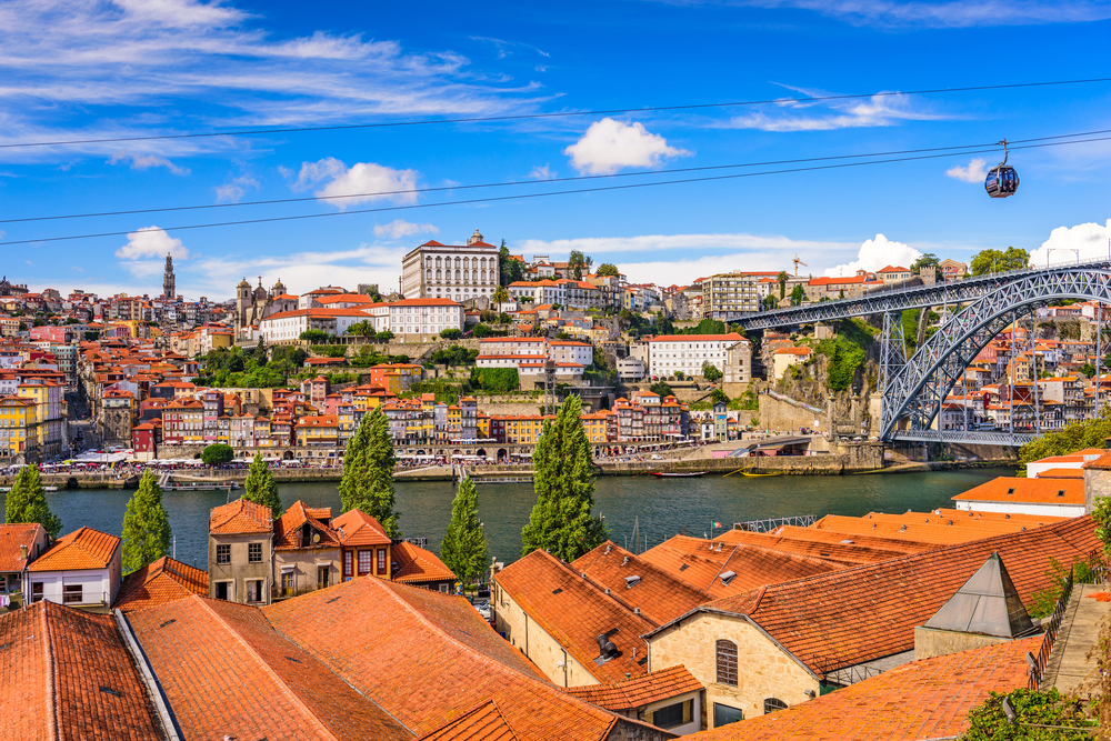 Scenic Porto city skyline with red roofs and Dom Luis I Bridge under a bright blue sky
