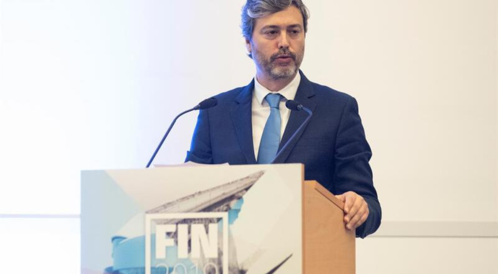 Man in a blue suit speaking behind a conference podium