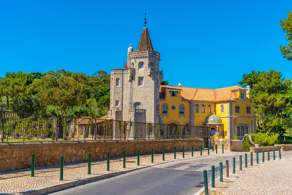 Historic Condes de Castro Guimarães museum with yellow wing and tiled turret under a clear blue sky
