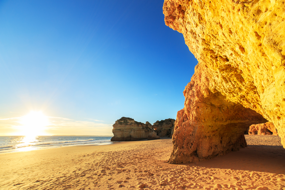 Golden sandy beach in the Algarve with dramatic towering red cliffs