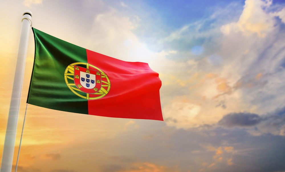 Portuguese flag flying proudly in the wind against a dramatic sky