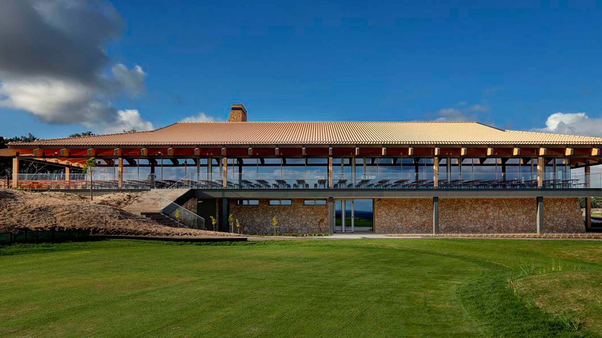 Modern West Cliffs Ocean & Golf Resort clubhouse with stone walls and glass facade