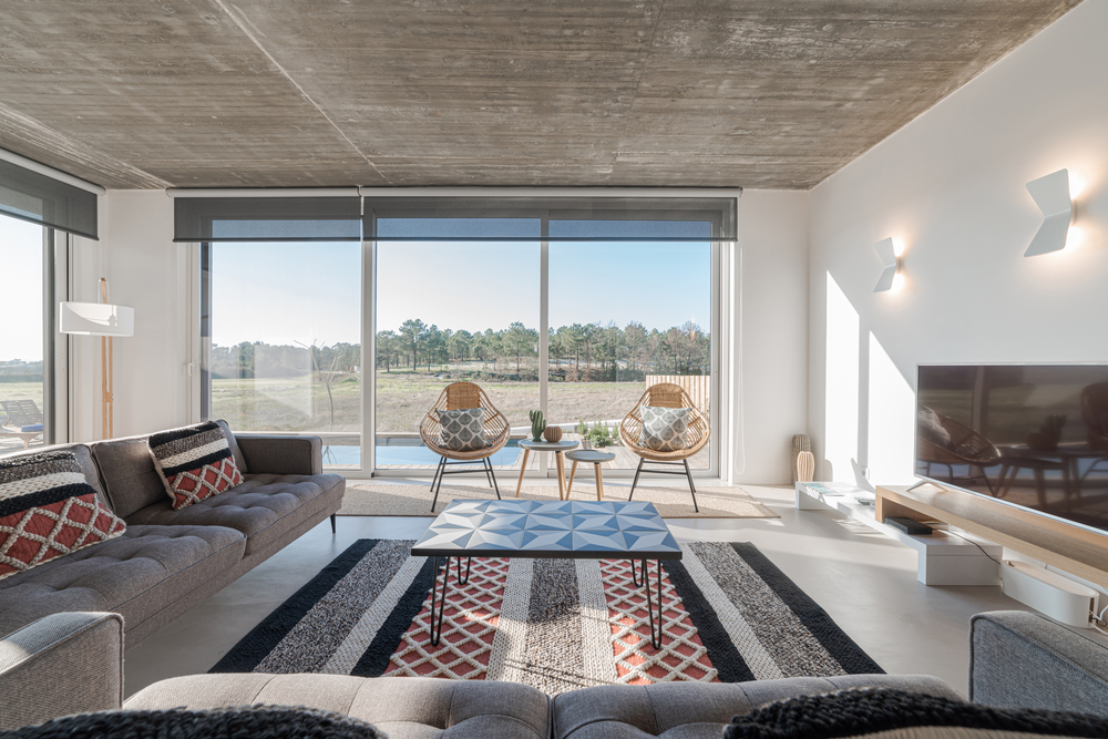 A stylish modern living room with large glass doors overlooking a natural rural landscape