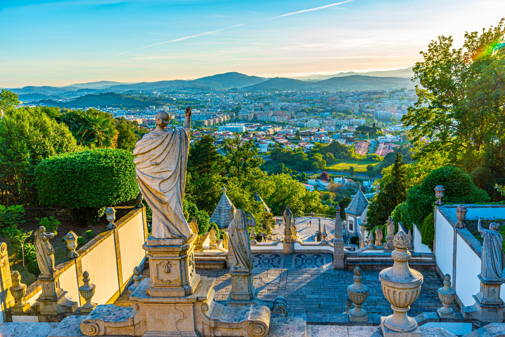 Stone statue points over the Braga city panorama from the historic Bom Jesus do Monte stairs