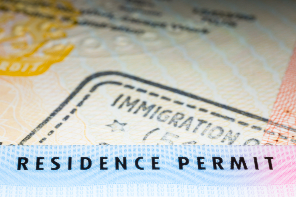 Close up view of an immigration entry stamp and "RESIDENCE PERMIT" text band on a passport page
