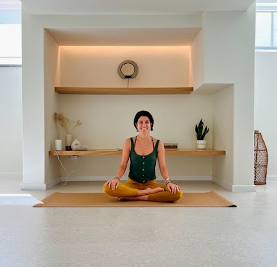 Smiling woman meditating in a bright, minimalist yoga studio on a mat