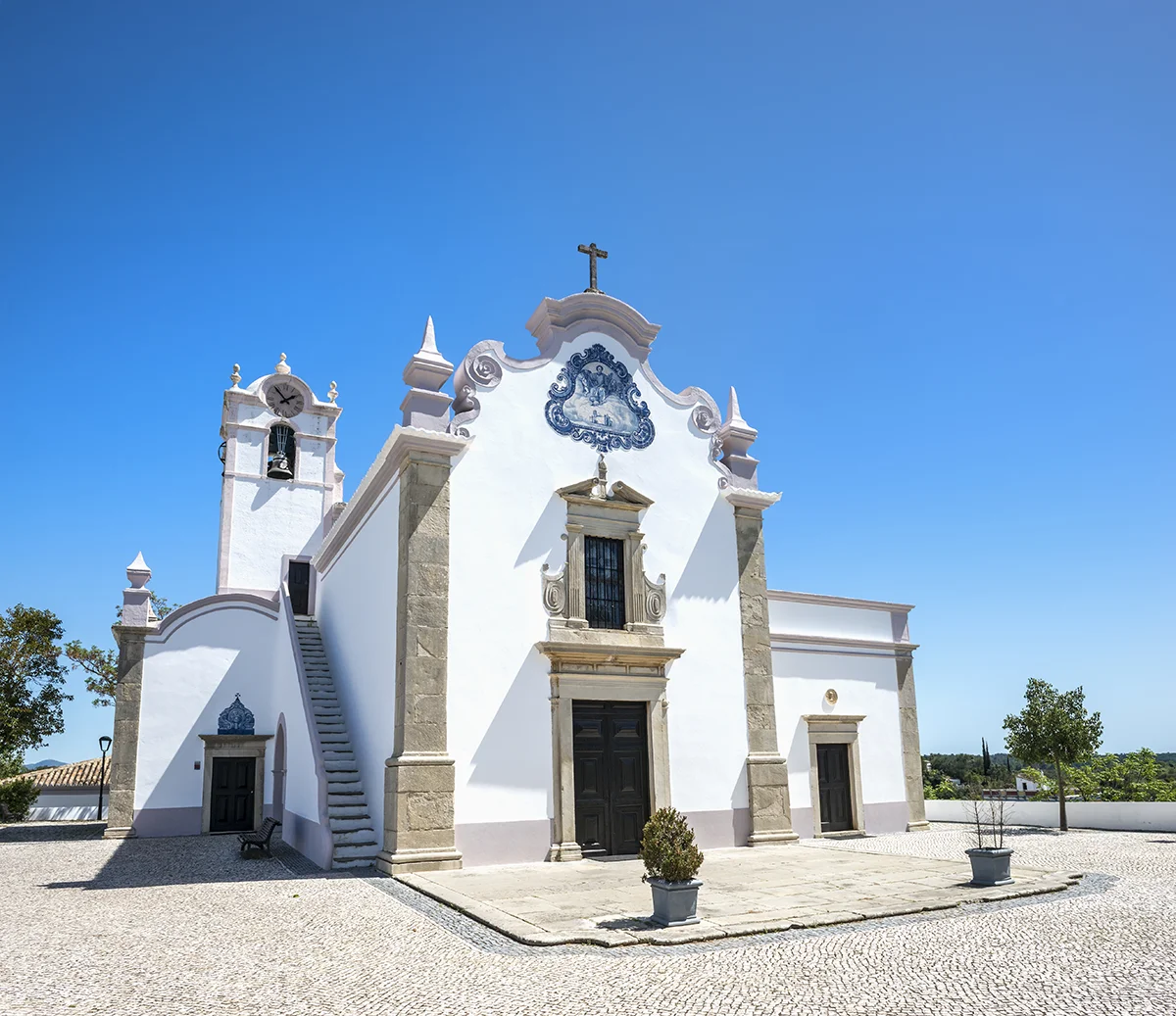 White Baroque façade of São Lourenço Church with blue azulejo tiles under a clear blue sky