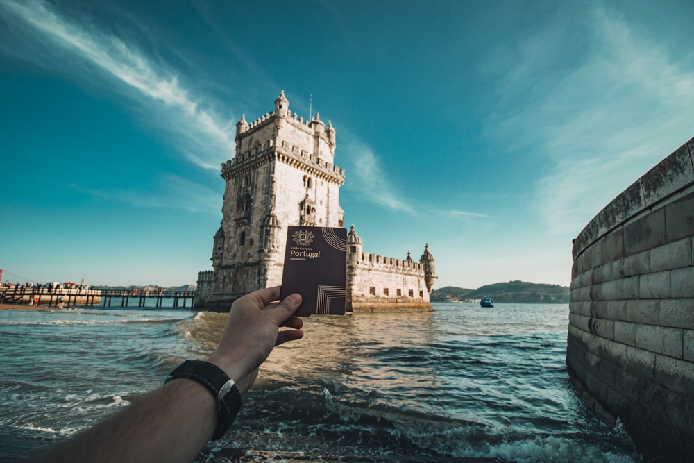 Portugal passport being held out in front of Portugal landmark