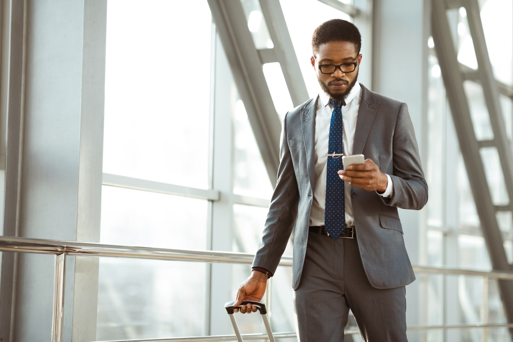 Successful entrepreneur in airport checking phone