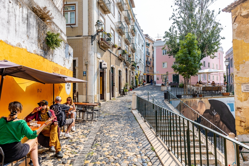 Cobbled street scene in Portugal with café and people enjoying coffee.