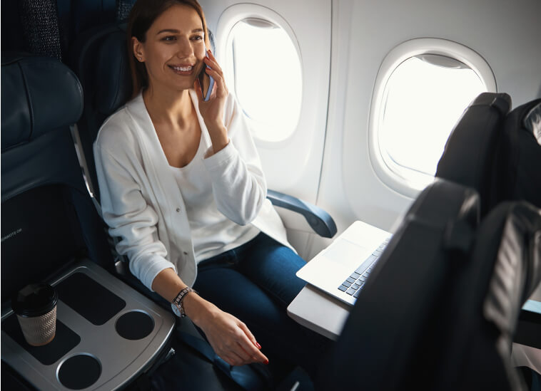 a woman using phone and laptop on a plane