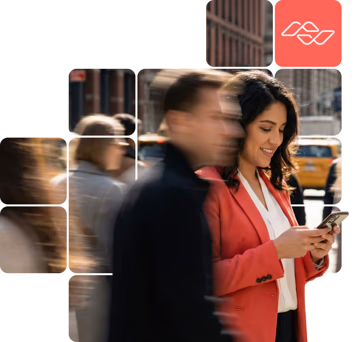 Woman in a red blazer smiling and using a smartphone on a busy city street