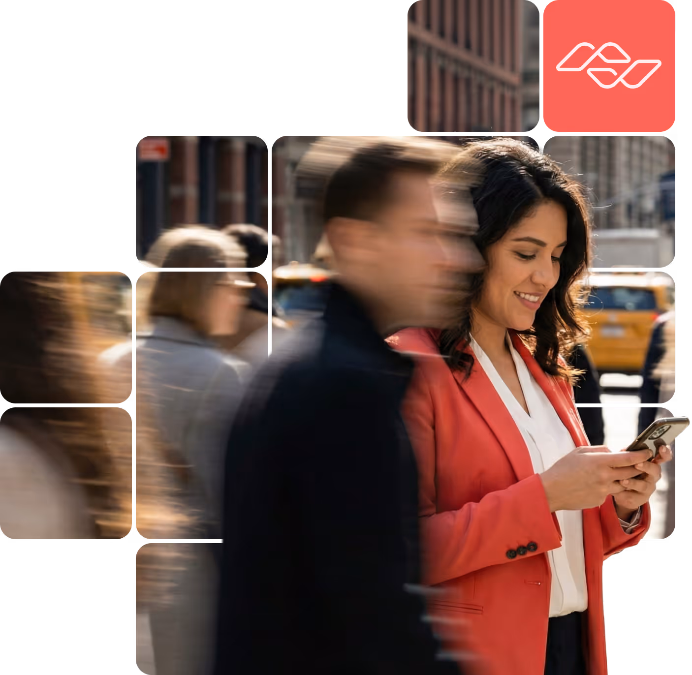Woman in a red blazer smiling and using a smartphone on a busy city street