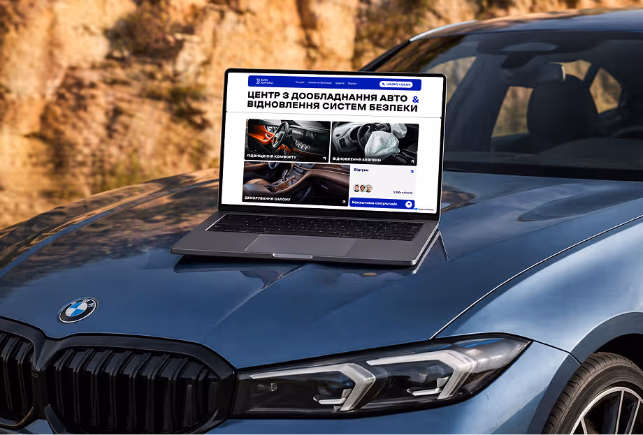 Ноутбук на капоті BMW із відкритою сторінкою сайту центру дообладнання авто та відновлення систем безпеки.