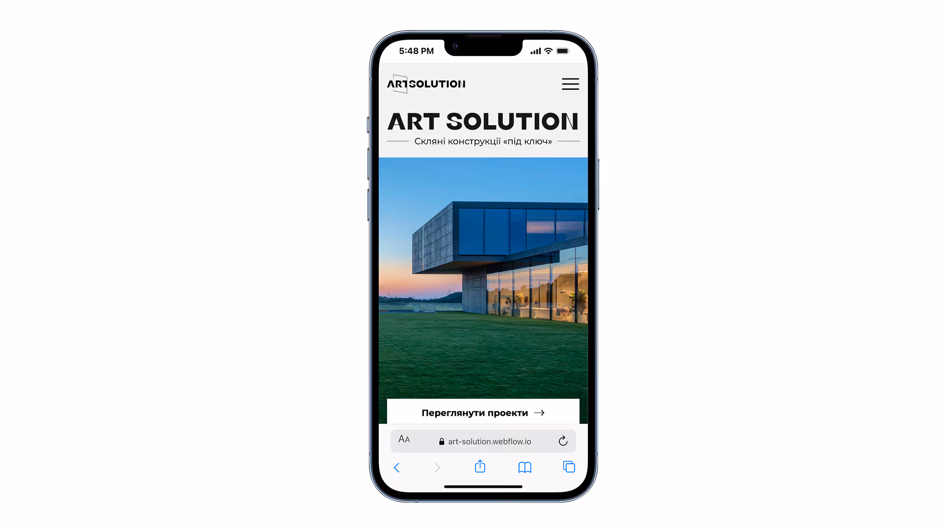 Смартфон із сайтом ART SOLUTION, що пропонує скляні конструкції під ключ, на фоні сучасної архітектури та зеленого газону.