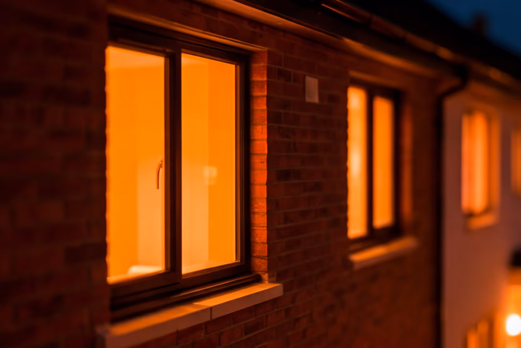 Exterior view of a brick building with warmly lit windows at night.