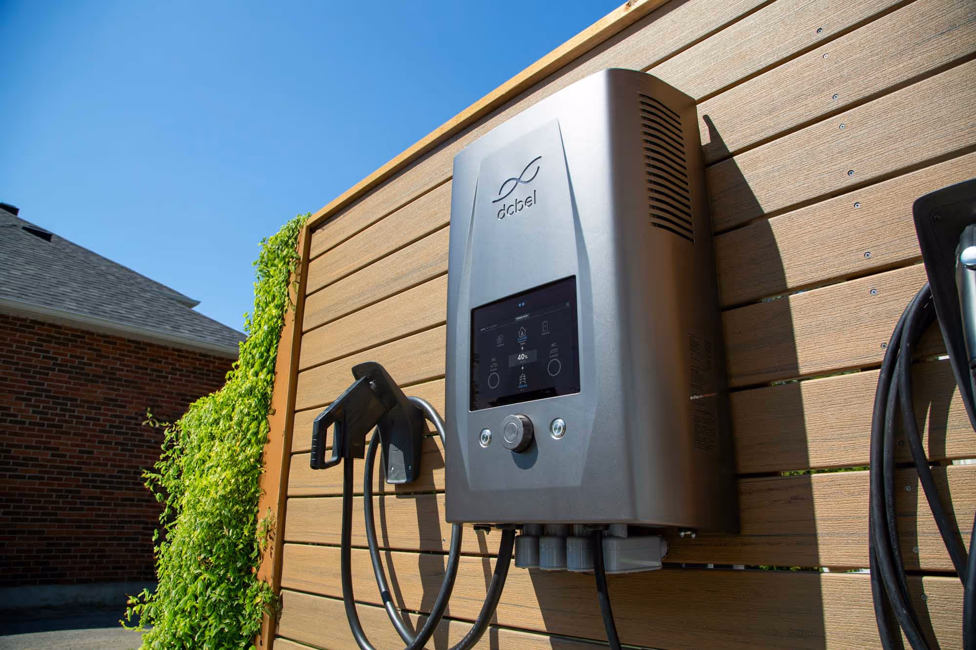 A residential electric vehicle charging station is mounted on a wooden wall.