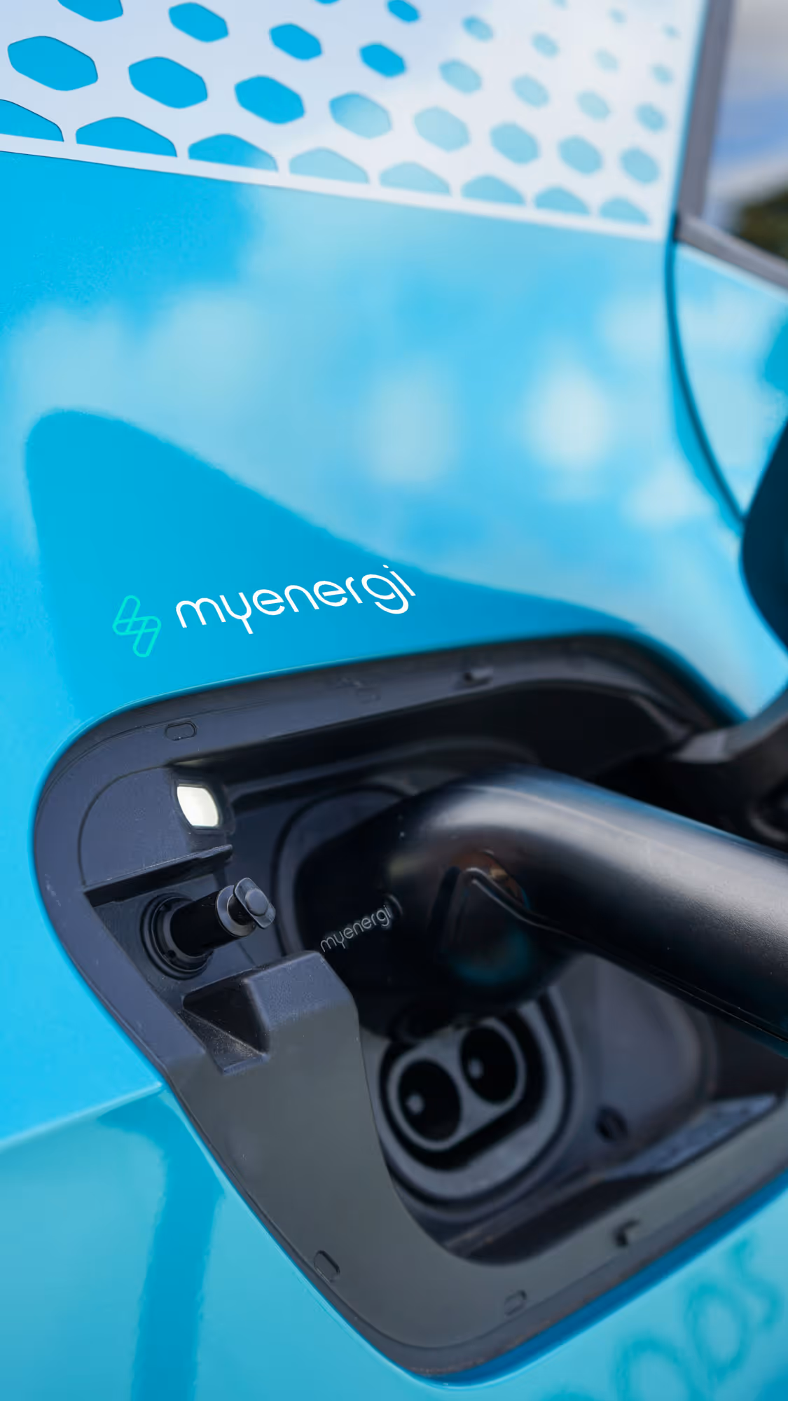 A close-up of an electric vehicle being charged, showing the charging cable connected to the port.