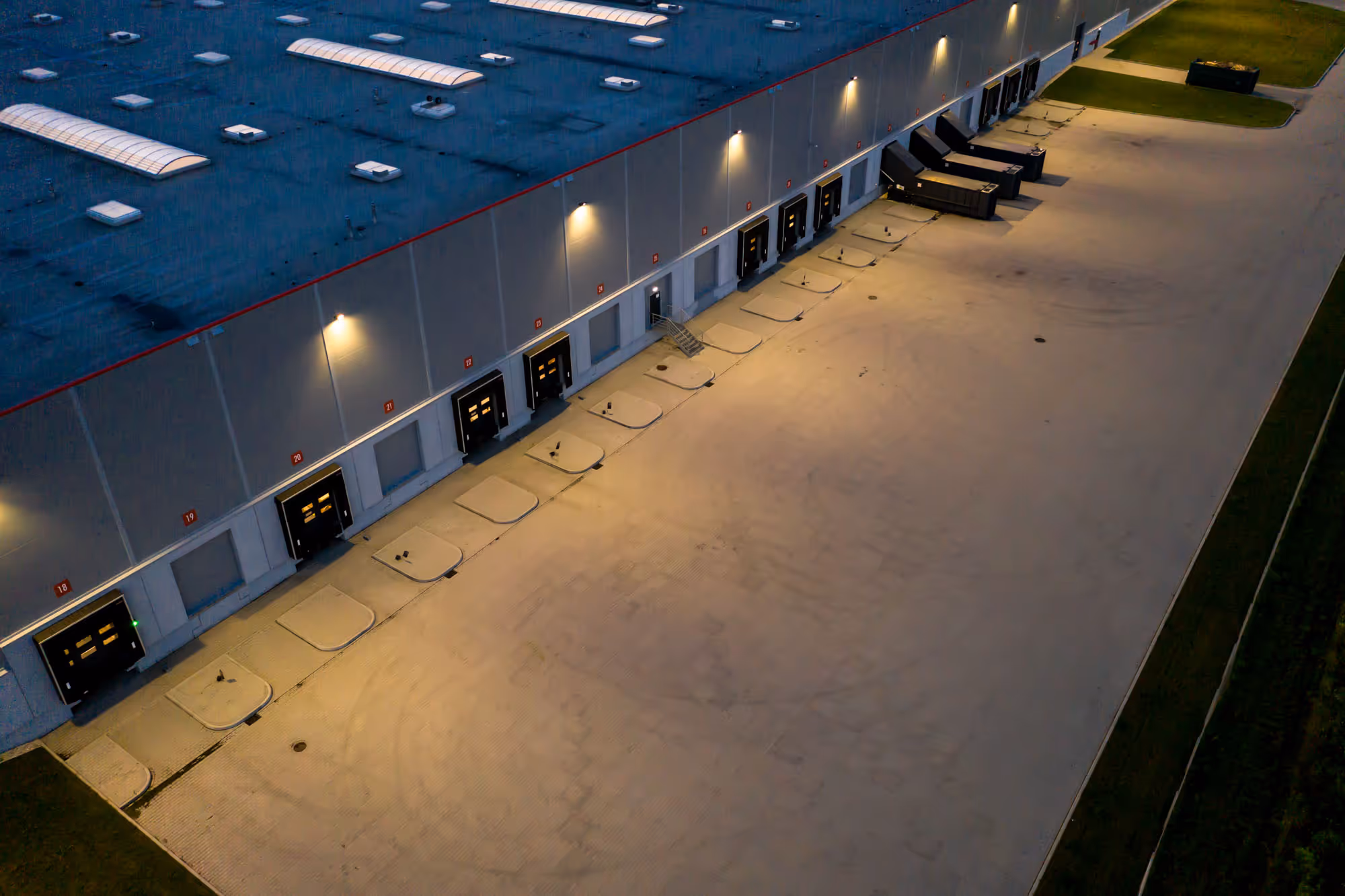 An aerial view of a warehouse loading dock with multiple closed bay doors and dim lighting.
