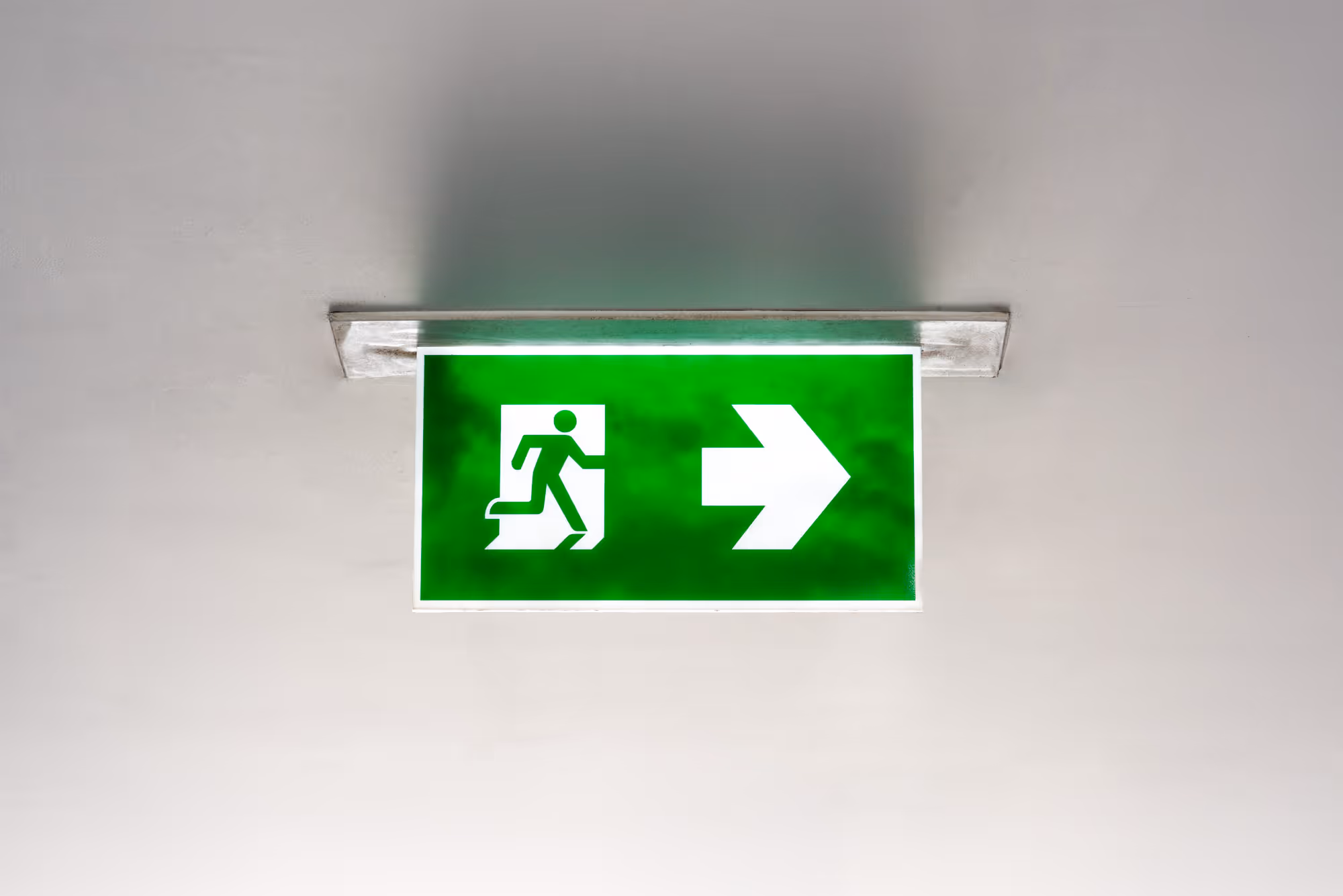 A green emergency exit sign with a running figure and a right-pointing arrow.