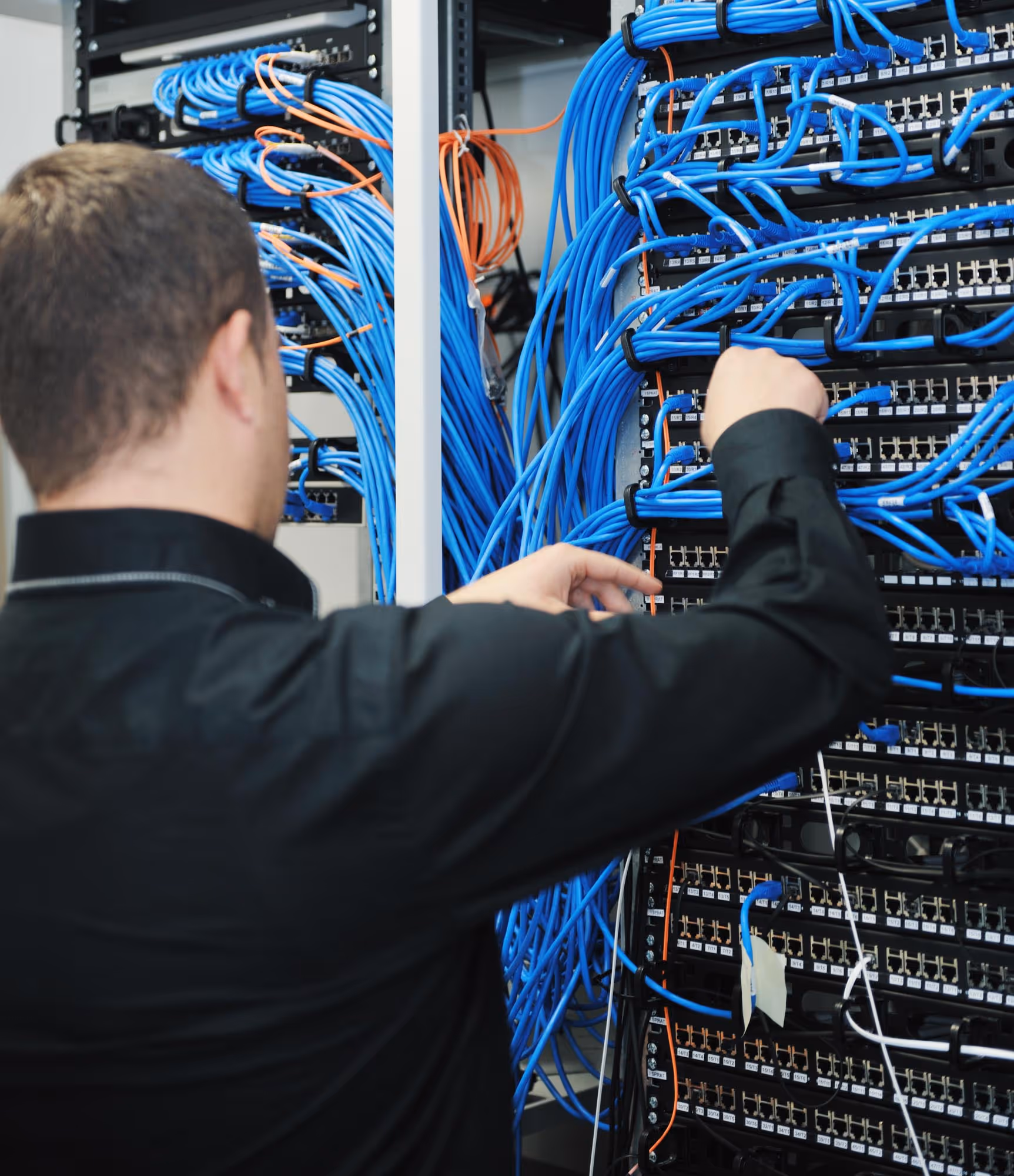 IT technician managing blue network cables in a server room rack.