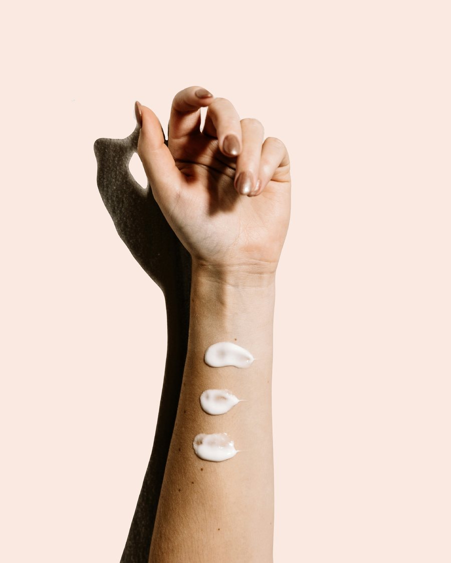 Underarm med klickar av kräm som masseras in