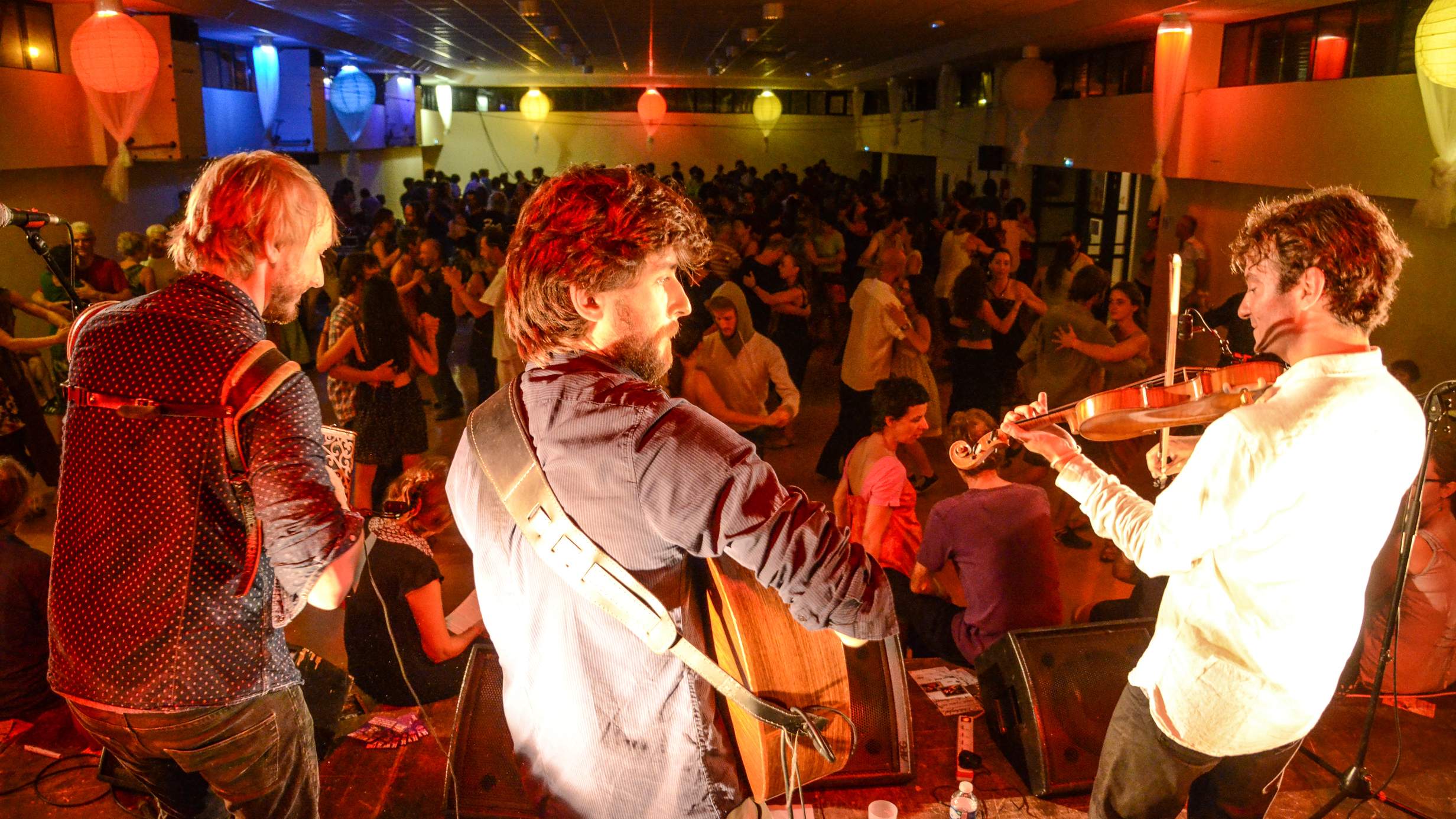 Orchestra and choir performing on stage with conductor in spotlight, surrounded by string instruments and harpsichord.
