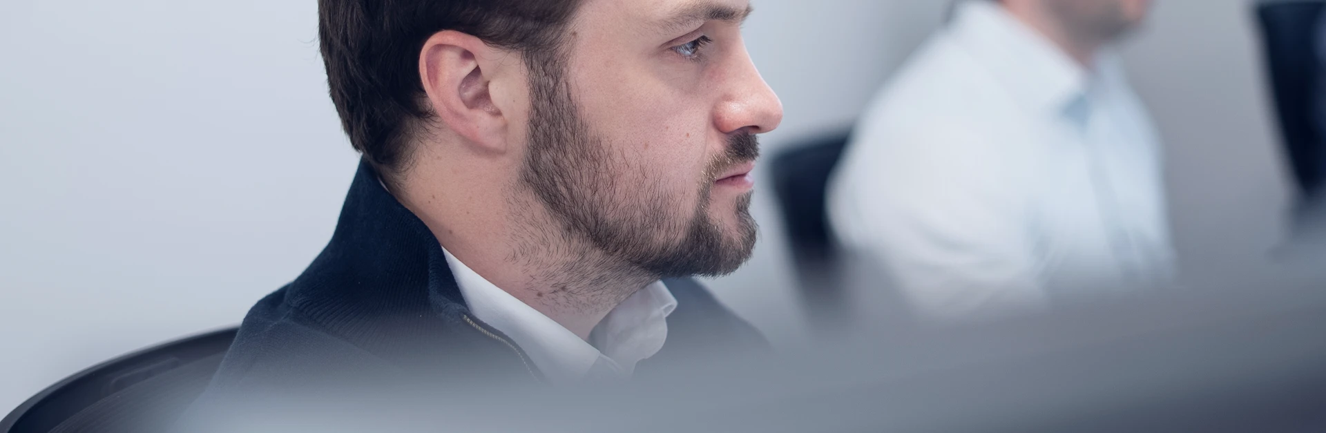Focused man with beard in profile sitting in an office environment.