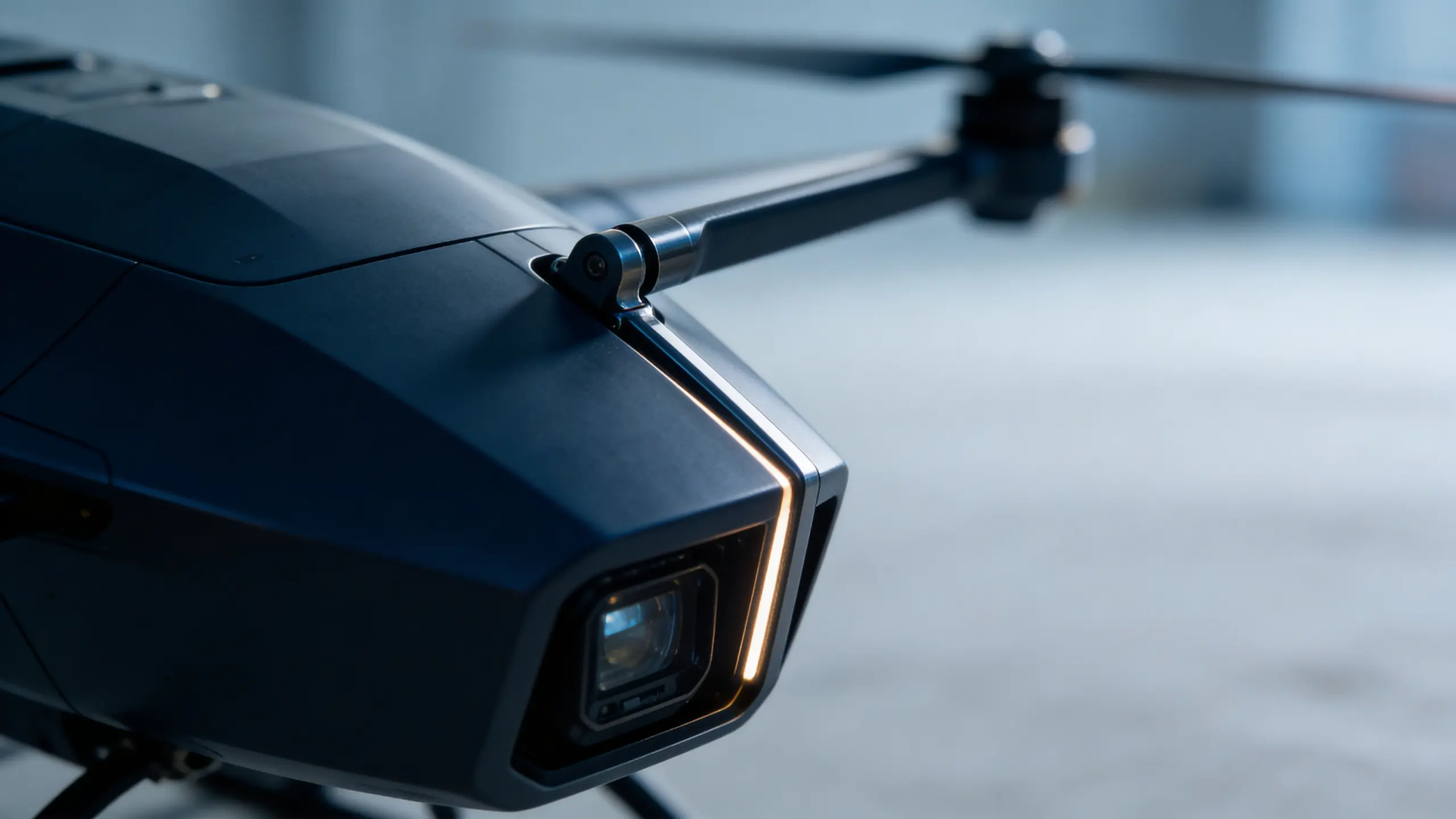 Close-up of a dark drone camera with an LED strip and one propeller arm in soft light.