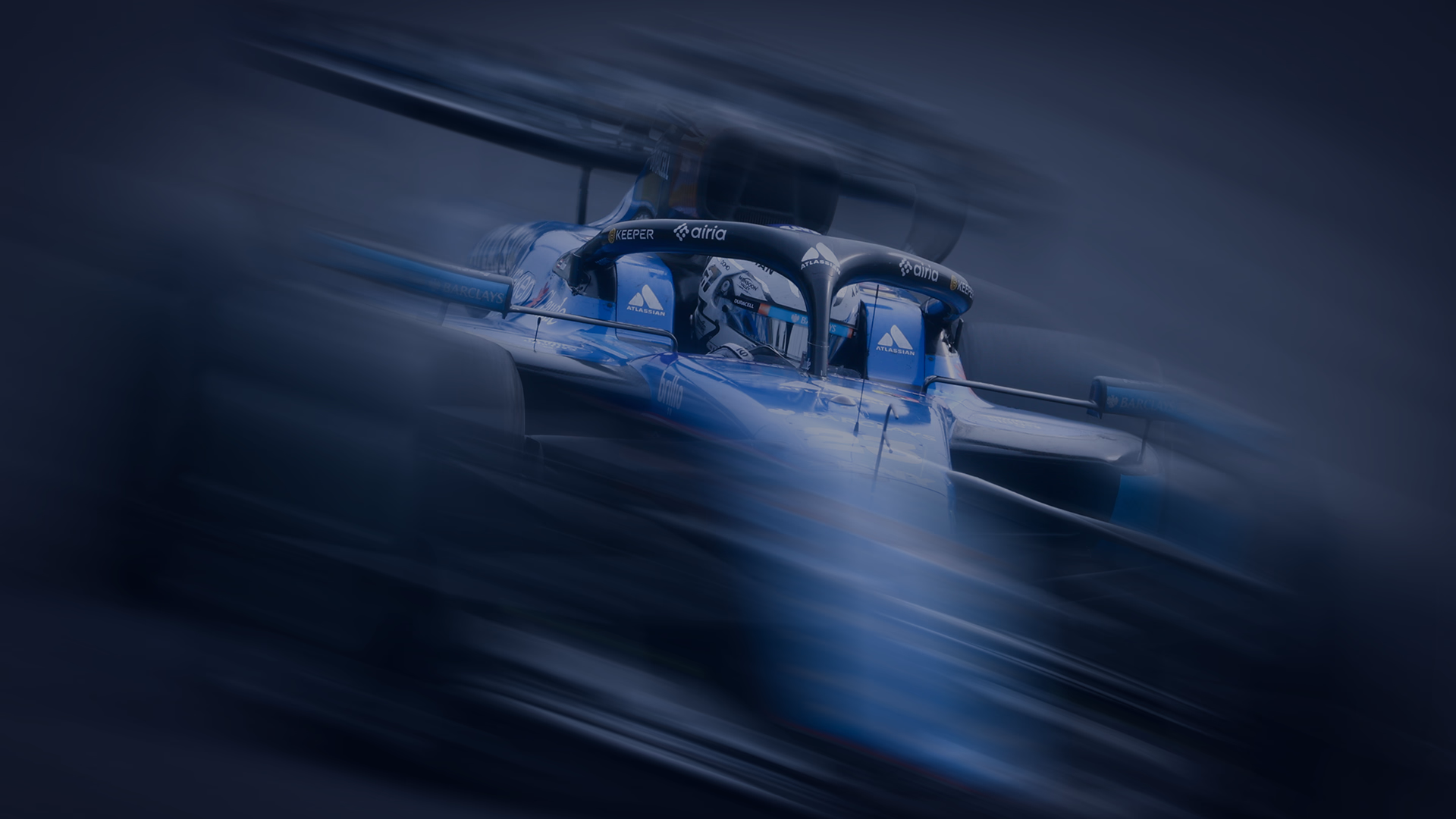 Williams Formula 1 race car speeding with blurred background and visible driver in helmet.