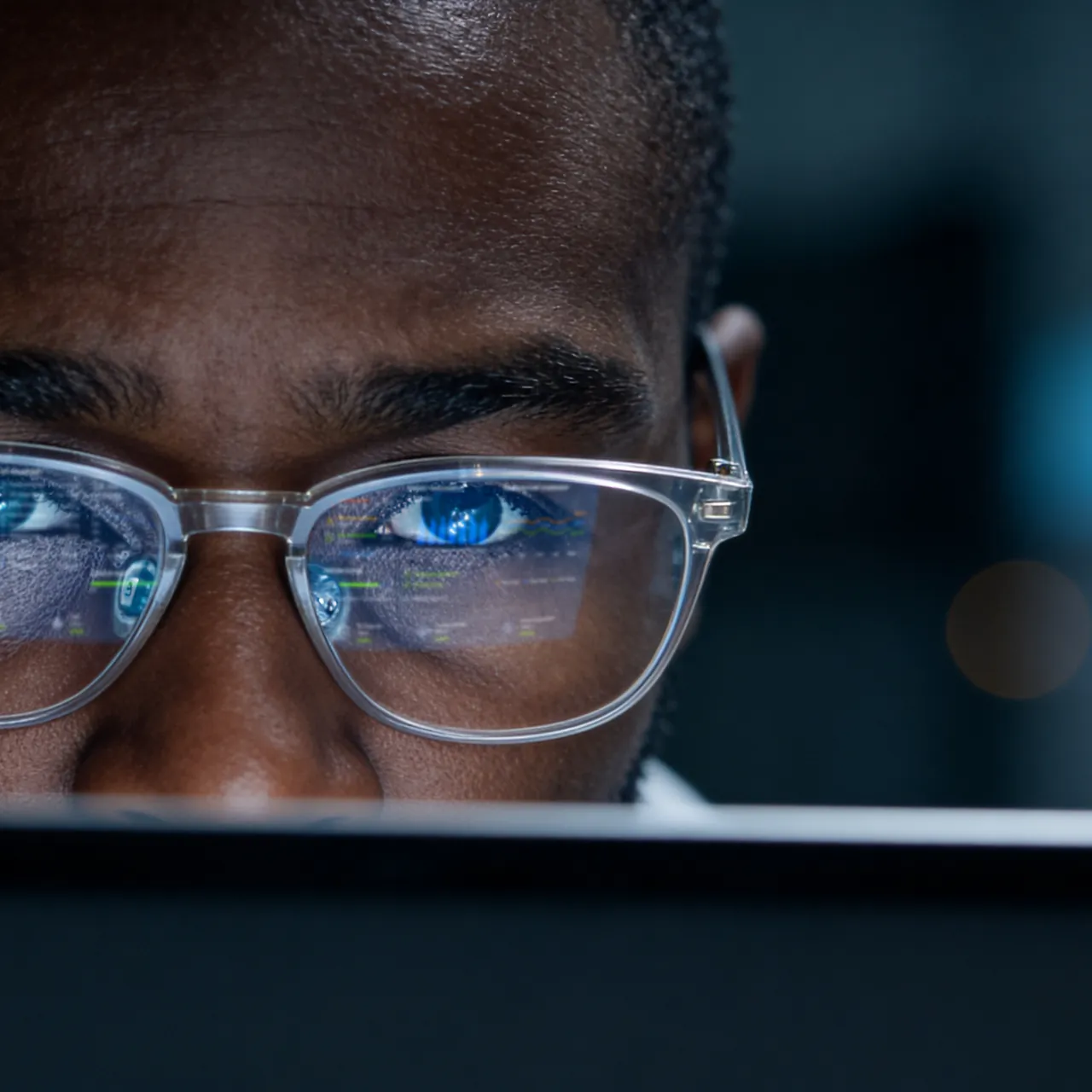 Close-up of man wearing glasses reflecting colourful physics informed machine learning charts on a screen in front of him.