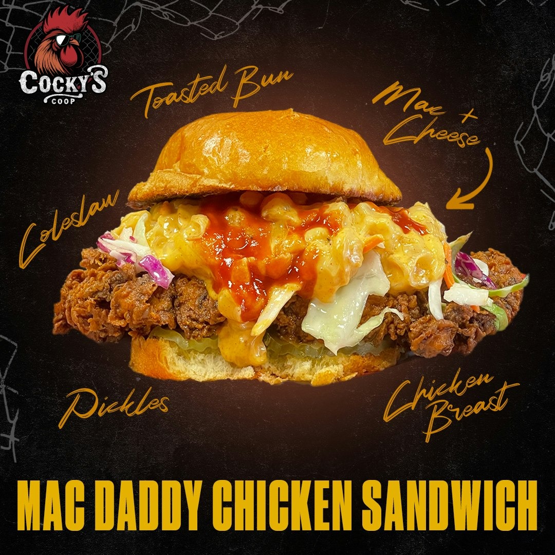 Mac Daddy Chicken Sandwich with toasted bun, fried chicken breast, coleslaw, pickles, and mac and cheese topped with sauce.