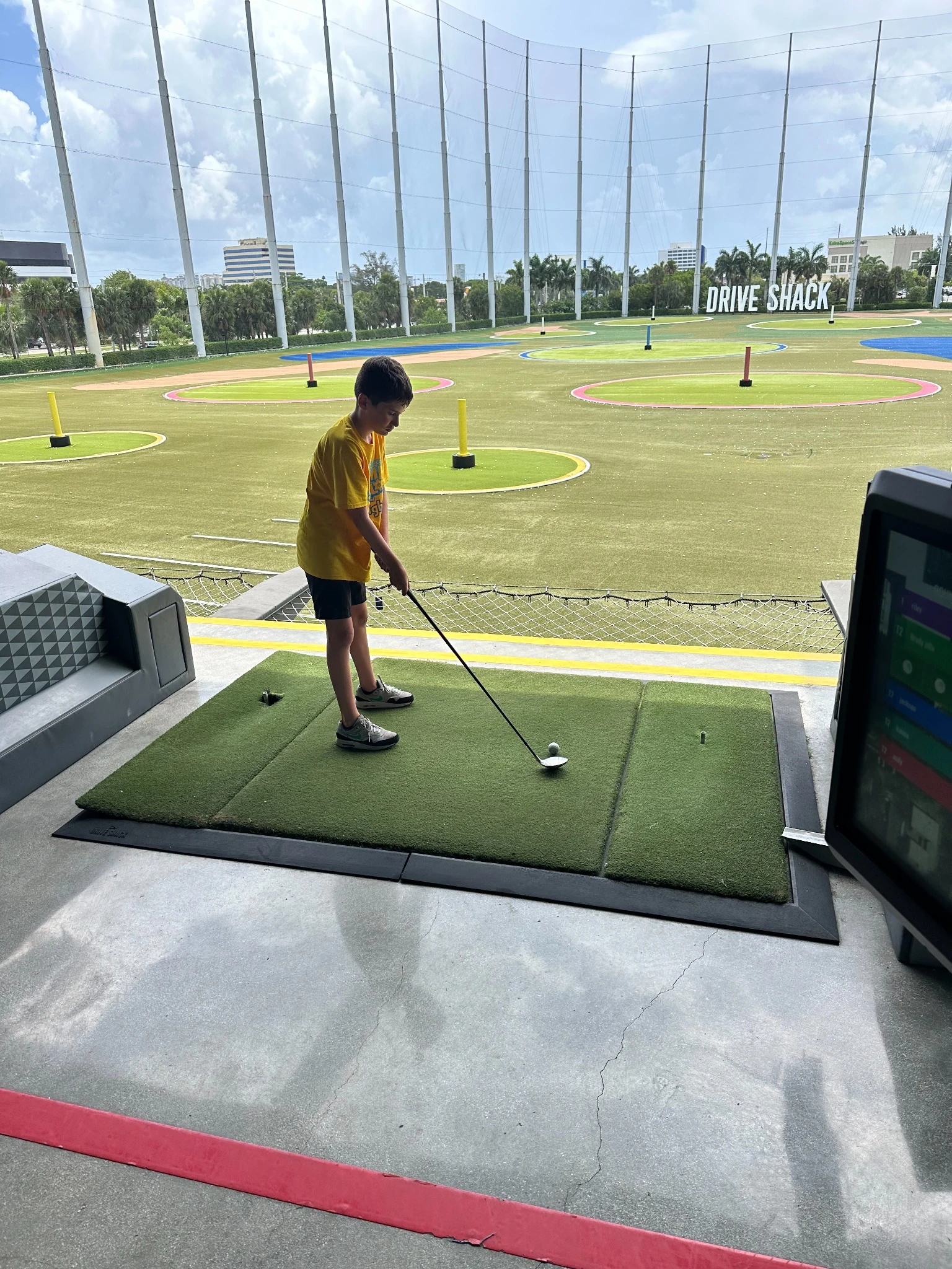 Boy learning to hit a golf ball at a summer camp activity in Boynton Beach